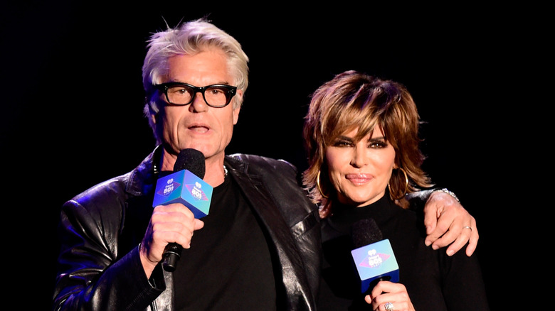 Harry Hamlin, Lisa Rinna in matching black, speaking onstage at the 2016 iHeart80s Party