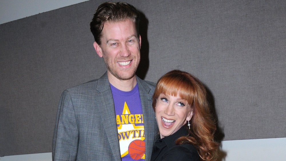 Randy Bick in a grey blazer and purple t-shirt, Kathy Griffin in a black outfit, both smiling