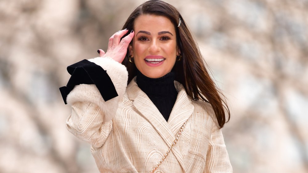 Lea Michele brushing her hair away from her face