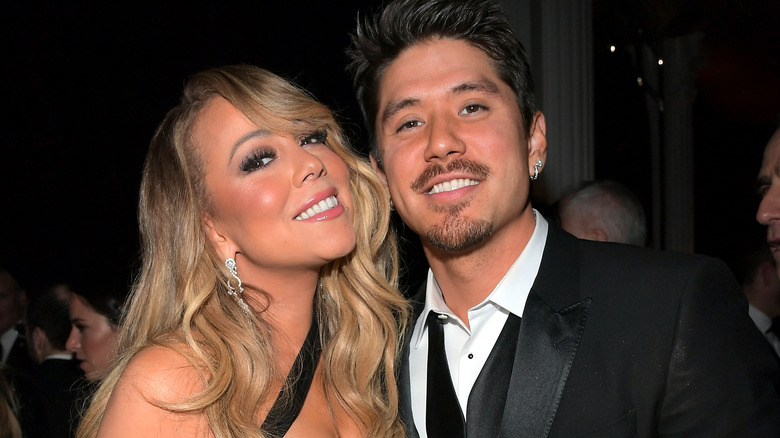 Mariah Carey and Bryan Tanaka stand together at party