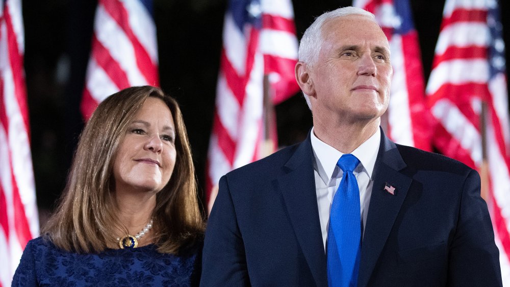 Karen and Mike Pence both gazing and smiling in front of USA flags