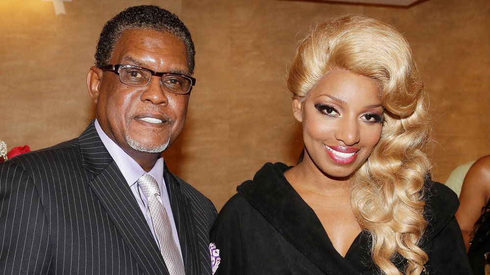 Gregg Leakes in a black pin-striped suit, NeNe Leakes with long blonde hair and a black dress
