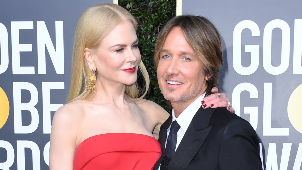 Nicole Kidman in a red dress with her arm around Keith Urban's shoulder