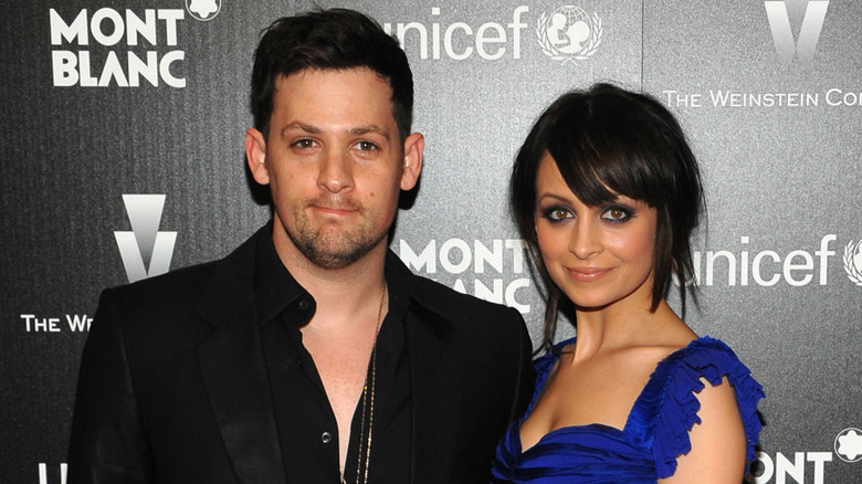 Joel Madden in a black blazer and open button-up shirt, Nicole Richie in a blue dress