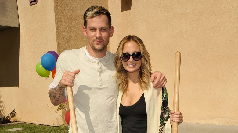 Joel Madden, Nicole Richie holding shovels and smiling outside