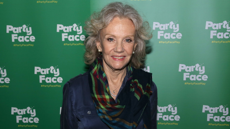 Hayley Mills smiling at a red carpet event against a green backdrop.