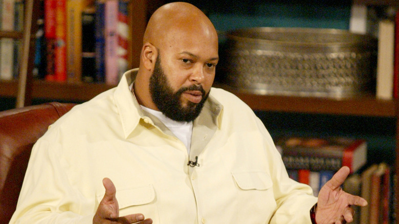 Suge Knight sitting in chair lifting hands up