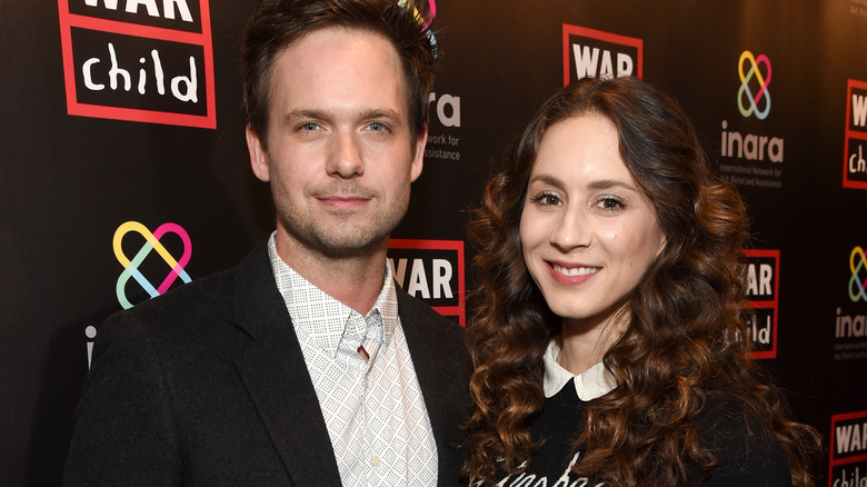 Patrick J. Adams smiles alongside Troian Bellisario at an event