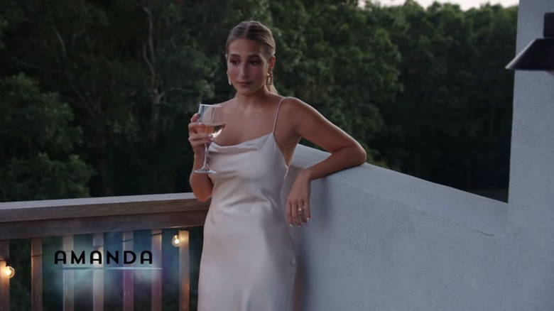 Amanda Batula standing on a balcony wearing a slip dress