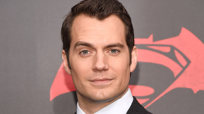Henry Cavill posing in front of Superman logo