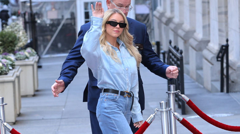 Sydney Sweeney waves to photographers in an American Eagle ensemble.