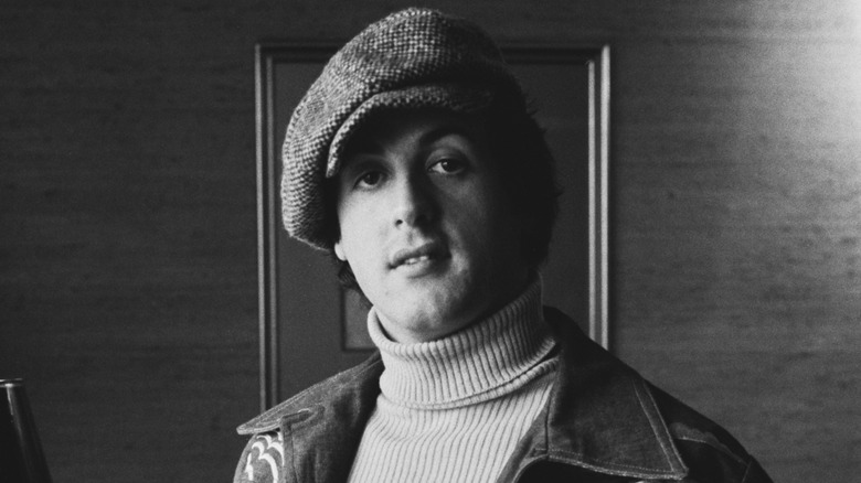 Young Sylvester Stallone wearing turtleneck sweater and newsboy cap