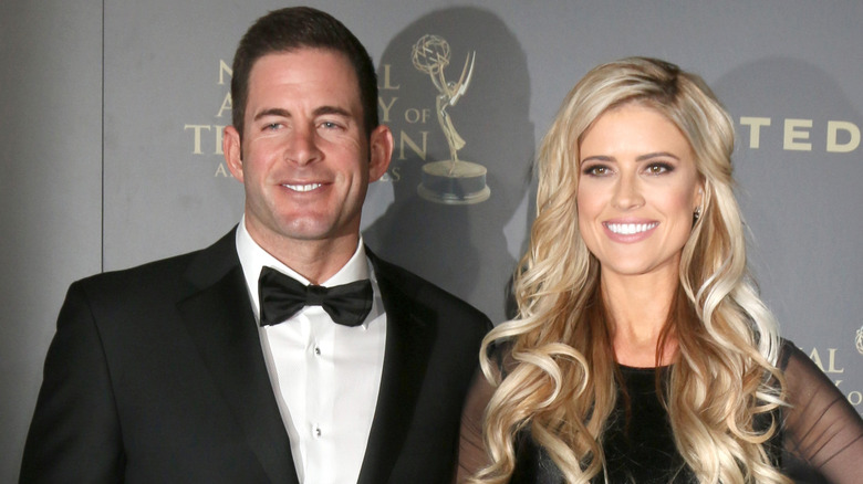 Tarek El Moussa, smiling, wearing a tux, standing next to Christina Haack, who's also smiling, wearing a black dress, 2017 Emmy's red carpet