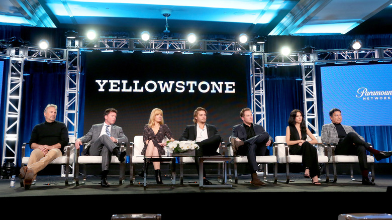 The cast of 'Yellowstone' sitting onstage together with Taylor Sheridan