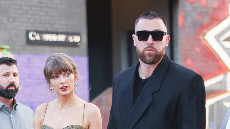 Taylor Swift and Travis Kelce standing next to each other on the street