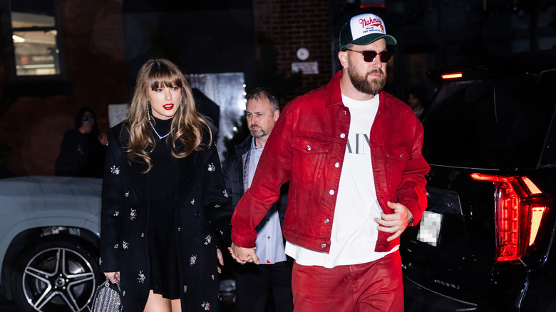 Taylor Swift and Travis Kelce walking at night hand in hand