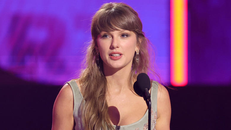 Taylor Swift speaking at a microphone.
