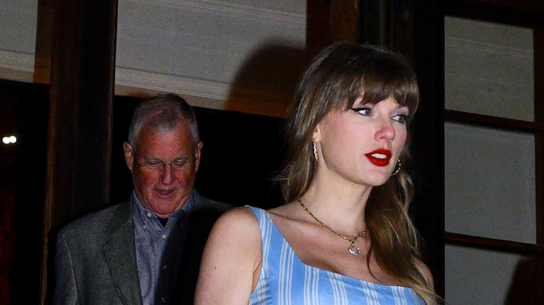 Taylor Swift walking in a blue dress with red lipstick