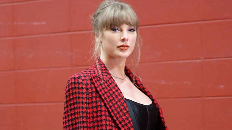 Taylor swift wearing a red pattern coat and matching skirt