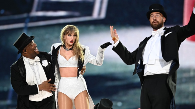 Dressed in a white bralette and matching bottoms, Taylor Swift gestures at Travis Kelce during a performance.