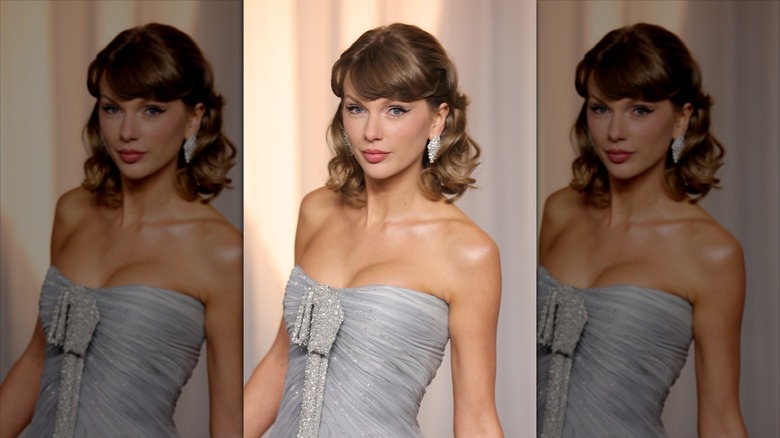 Taylor Swift posing in a strapless grey dress while sporting curly hair
