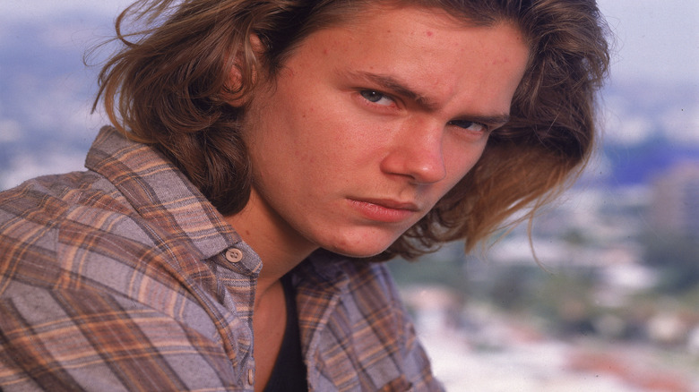 River Phoenix posing in front of blue background
