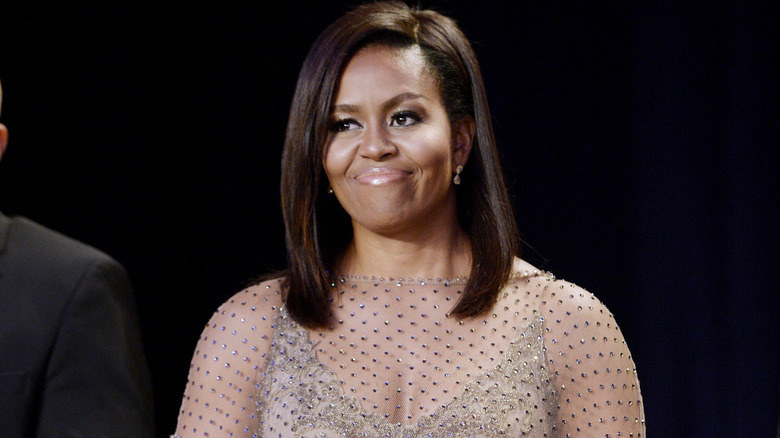 Michelle Obama is all smiles at an event wearing a sheer dress