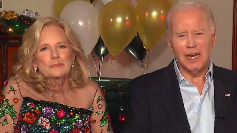 Dressed in a multicolored number with a sheer neckline, Jill Biden looks at the camera as Joe Biden talks