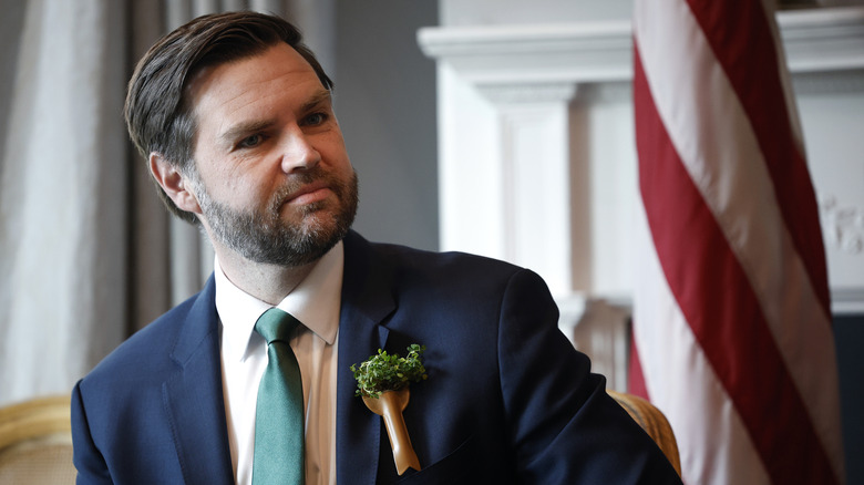 JD Vance seated in front of an American flag