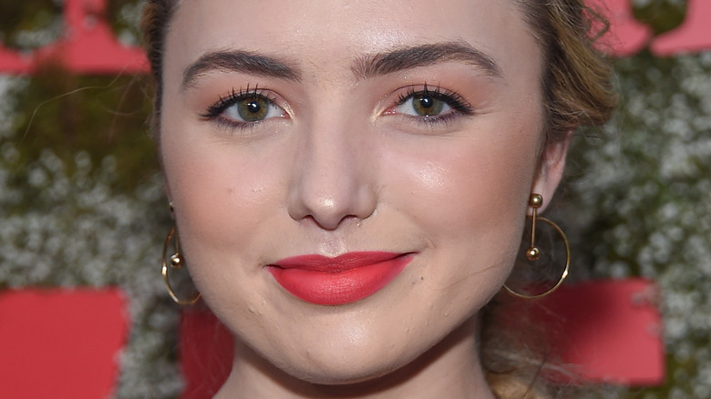 Peyton List smiles and wears dangle hoop earrings