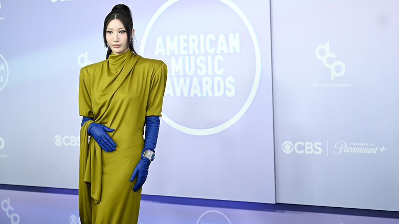 Ejae wearing a draped green dress and blue opera-length gloves at the 2026 AMAs.