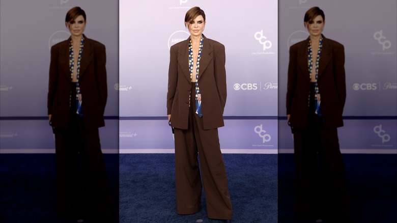 Lisa Rinna wearing a baggy brown suit and undone polka-dot tie featuring an image of JFK at the 2026 AMAs.
