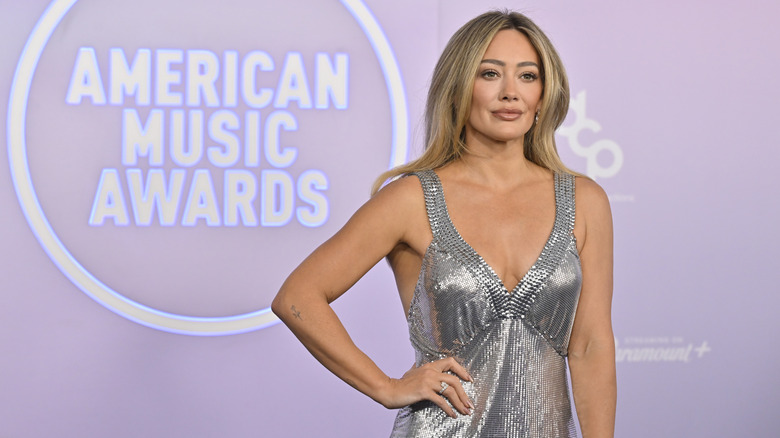 Hilary Duff wearing a silver chainmail dress on the red carpet at the 2026 AMAs.