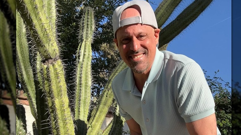 Gino Palazzolo smiling next to a big cactus plant in a light green shirt and ballcap