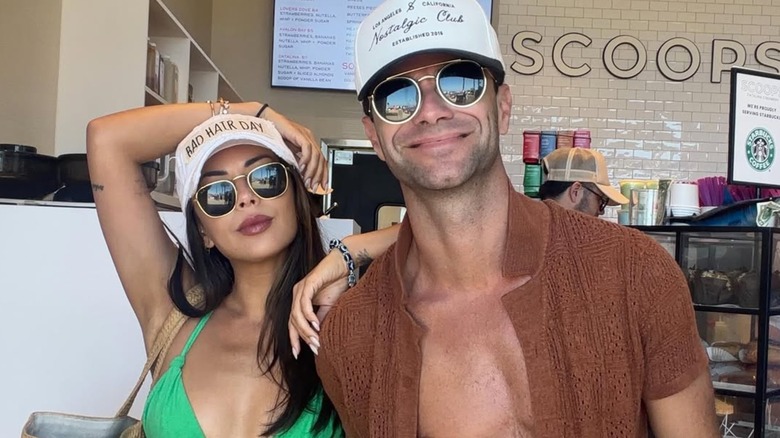 Janel Parrish posing for a photo in a green bikini and sunglasses