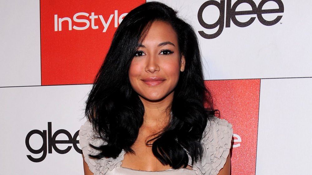 Naya Rivera smiling and posing on the red carpet of a Glee event