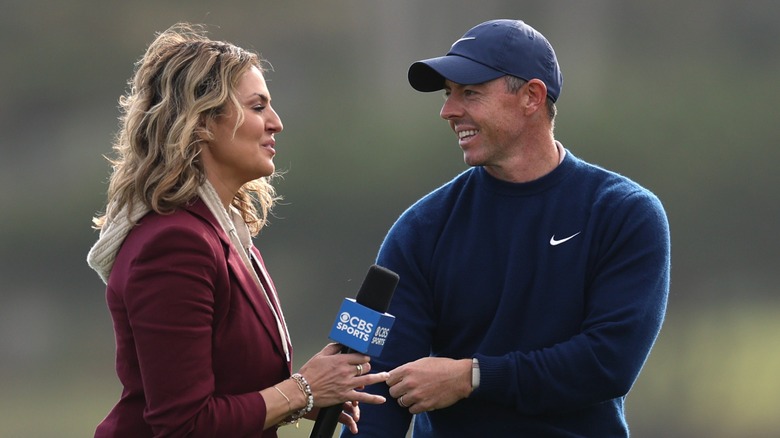 Amanda Balionis stretches a microphone toward golfer Rory McIlroy.