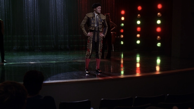 Mr. Schuester stands on the stage in a matador outfit in "Glee"