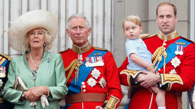 Queen Camilla, King Charles, and Prince William holding Prince Louis