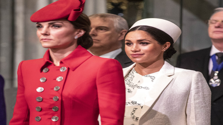 Kate Middleton standing in front of Meghan Markle