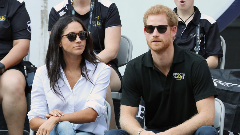 Meghan Markle Prince Harry seated and wearing sunglasses