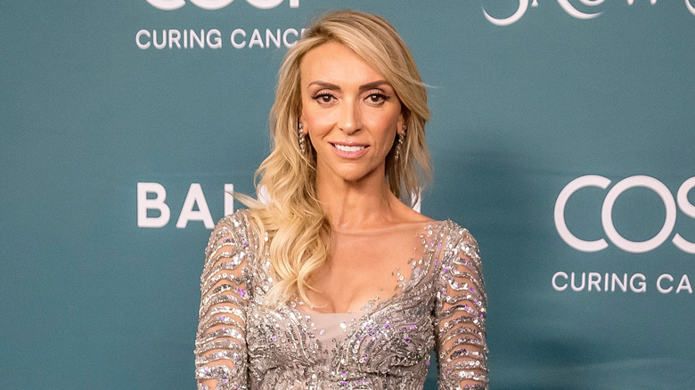Giuliana Rancic smiling while posing on a 2024 red carpet in a sparkly dress