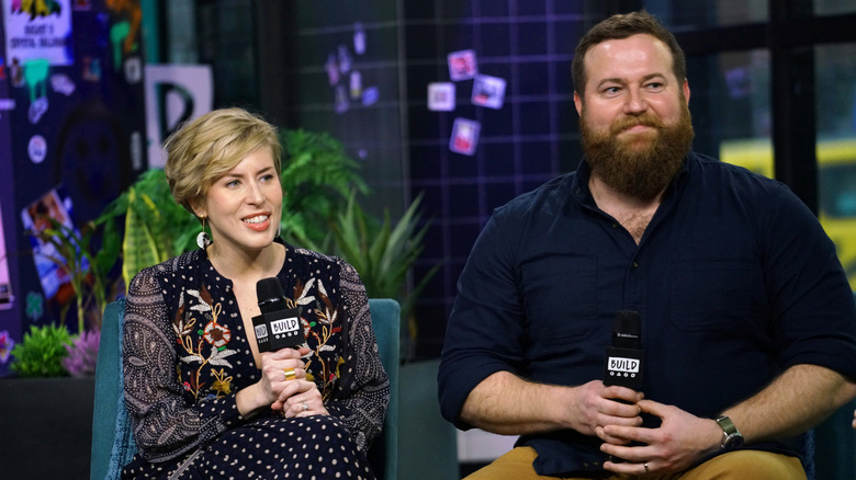 Erin and Ben sitting on a couch holding microphones
