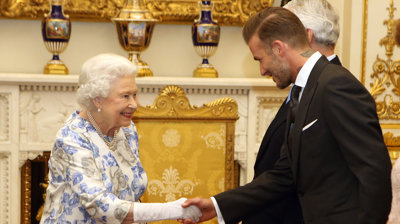 Queen Elizabeth II and David Beckham smiling at each other