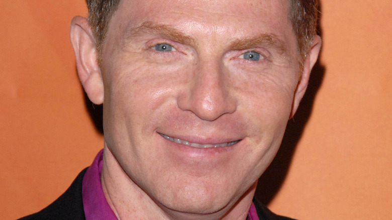 Bobby Flay smiles in a purple shirt