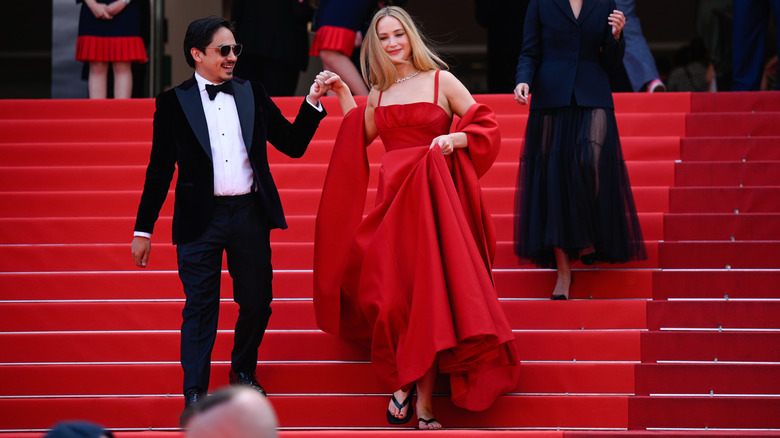 Jennifer Lawrence holds up her gown to reveal flip-flops on the Palais des Festivals steps.