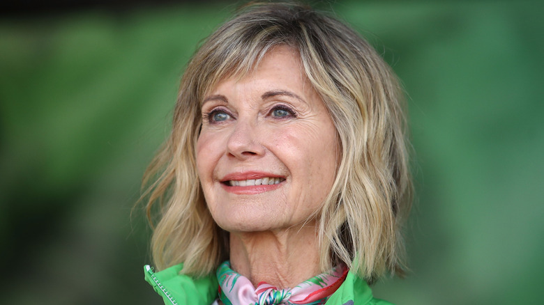 olivia newton-john smiling green background
