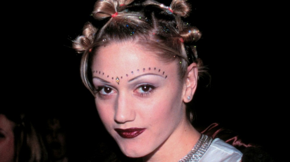 Gwen Stefani wearing a bindi and beads above her eyes with a knotted braid hairstyle