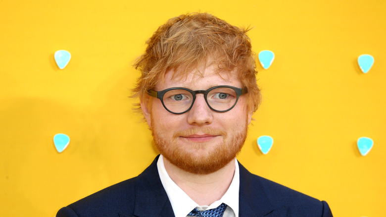 Ed Sheeran posing against yellow background