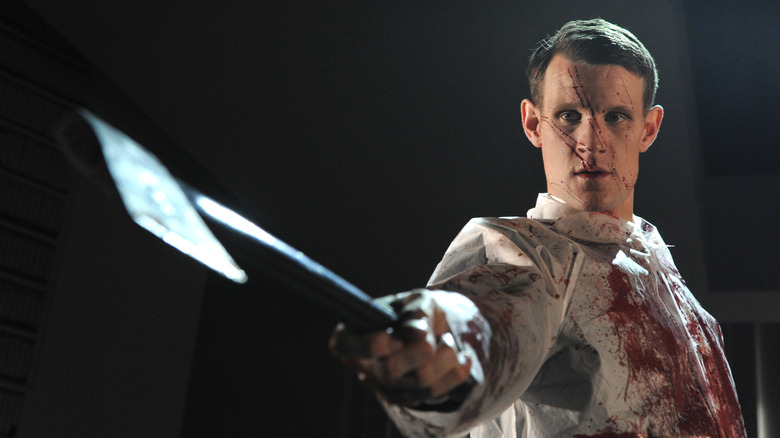 Matt Smith in a bloody coat holding an axe as Patrick Bateman in American Psycho the musical